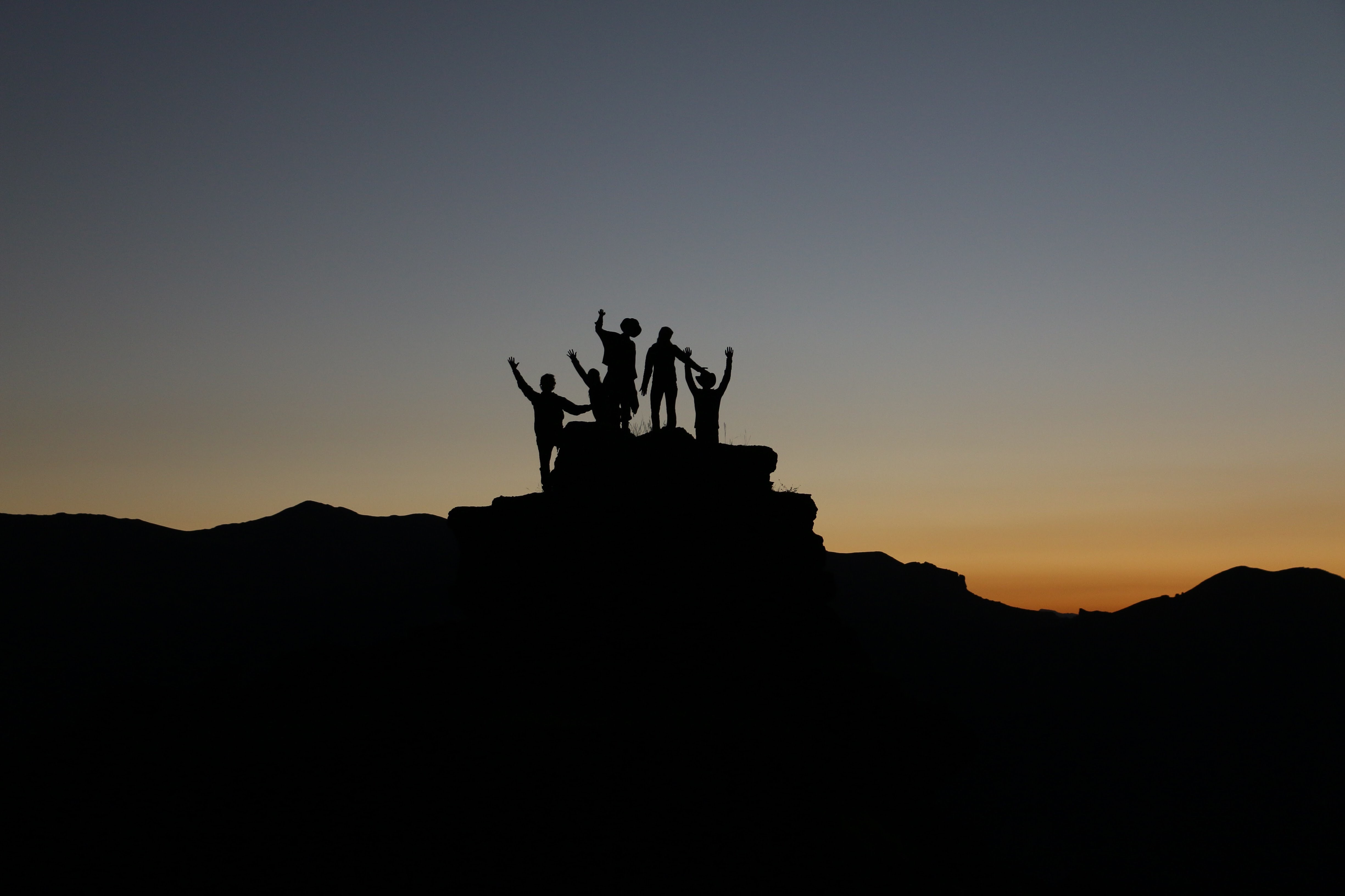 small group of people mountaintop silhouette