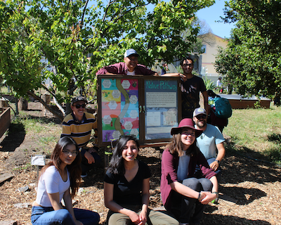 Environmental studies students pose near a school sign