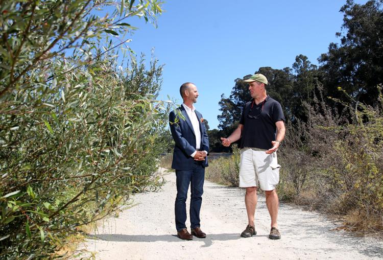 Fred is standing next to Scott Waltz, who's wearing a suit. The two men are standing on a bike trail.