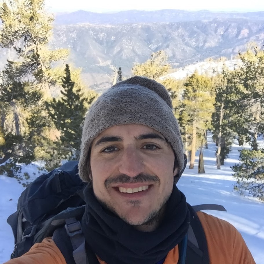 Jimmy poses in front of a snow covered forest