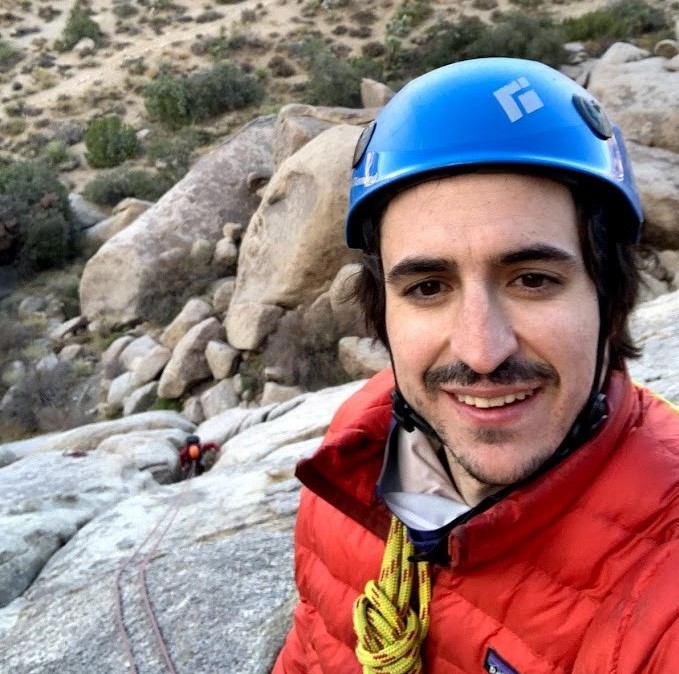 Dr. Jimmy Guilinger posing amongst rocks with a helmet