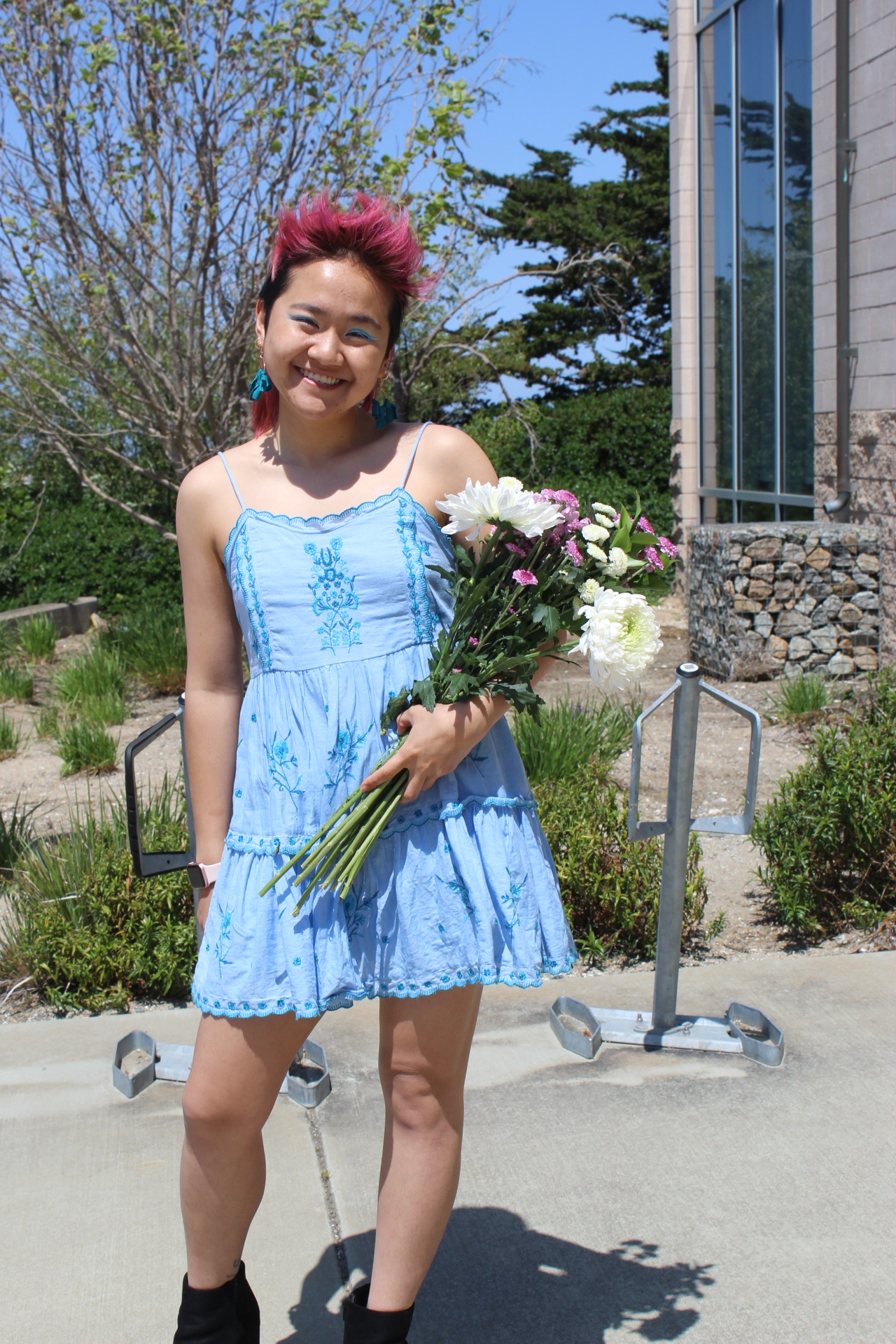 Wendy Feng poses in a blue dress with a bouquet of flowers