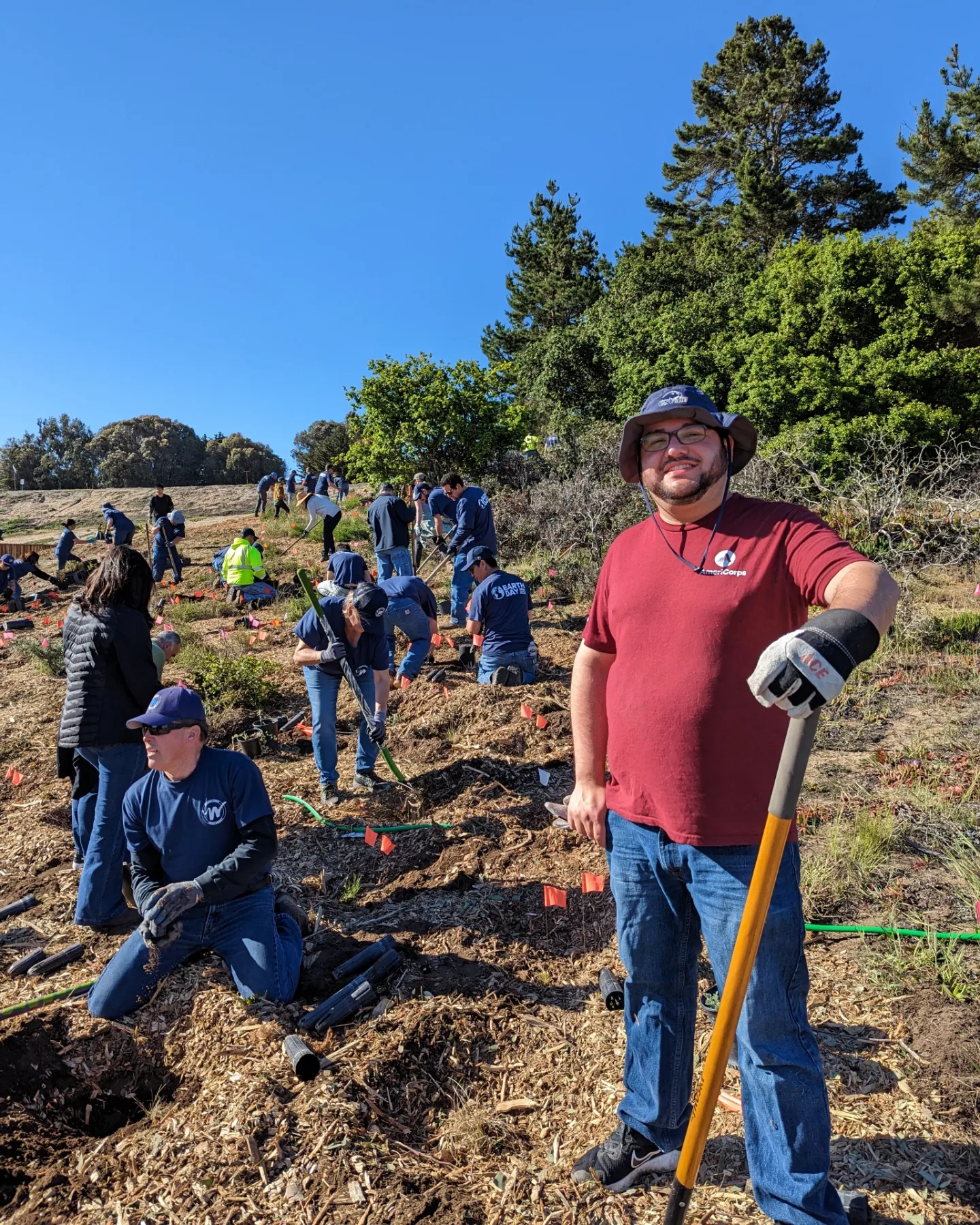 Jacob smiling and holding a shovel while planting a tree