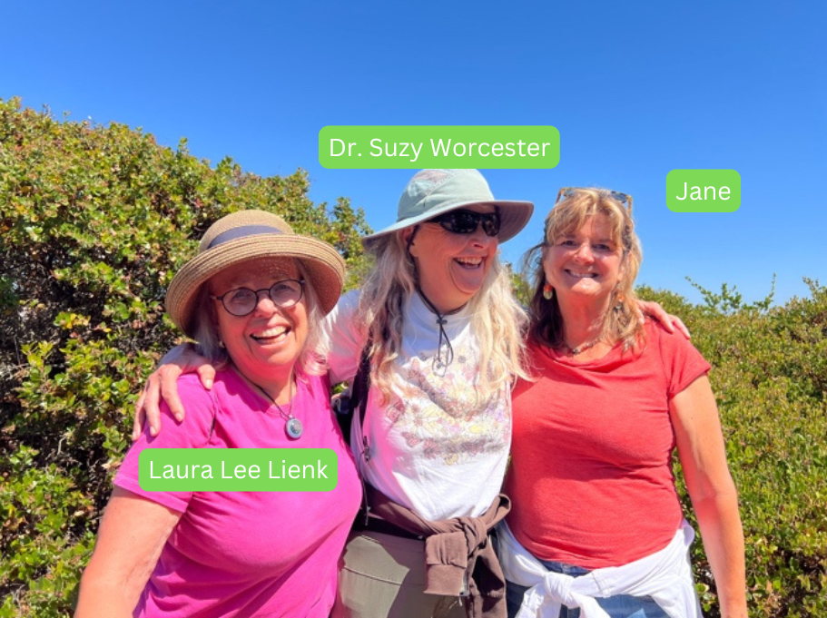 Three women smiling together outdoors under a clear blue sky.