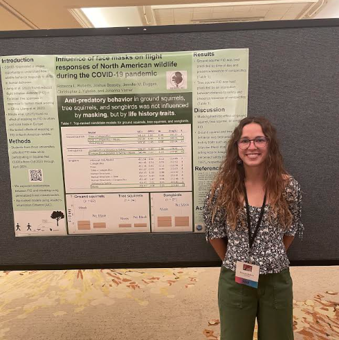 Rebecca is pictured smiling next to her conference poster