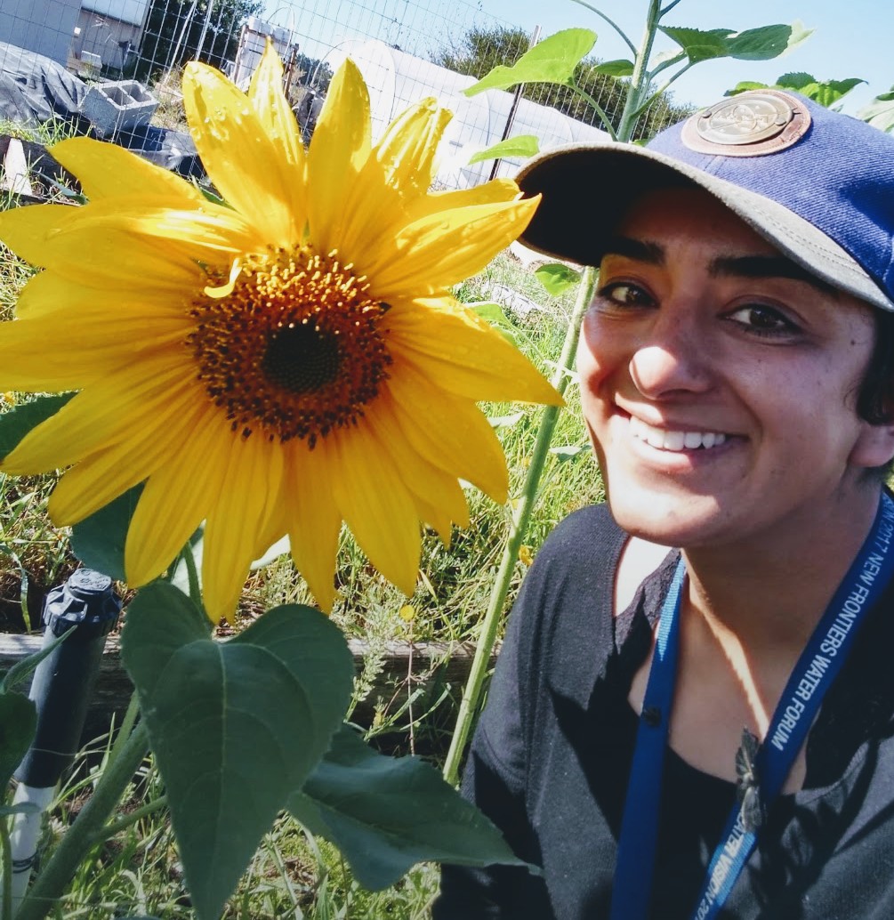 Rahil poses next to a large sunflower