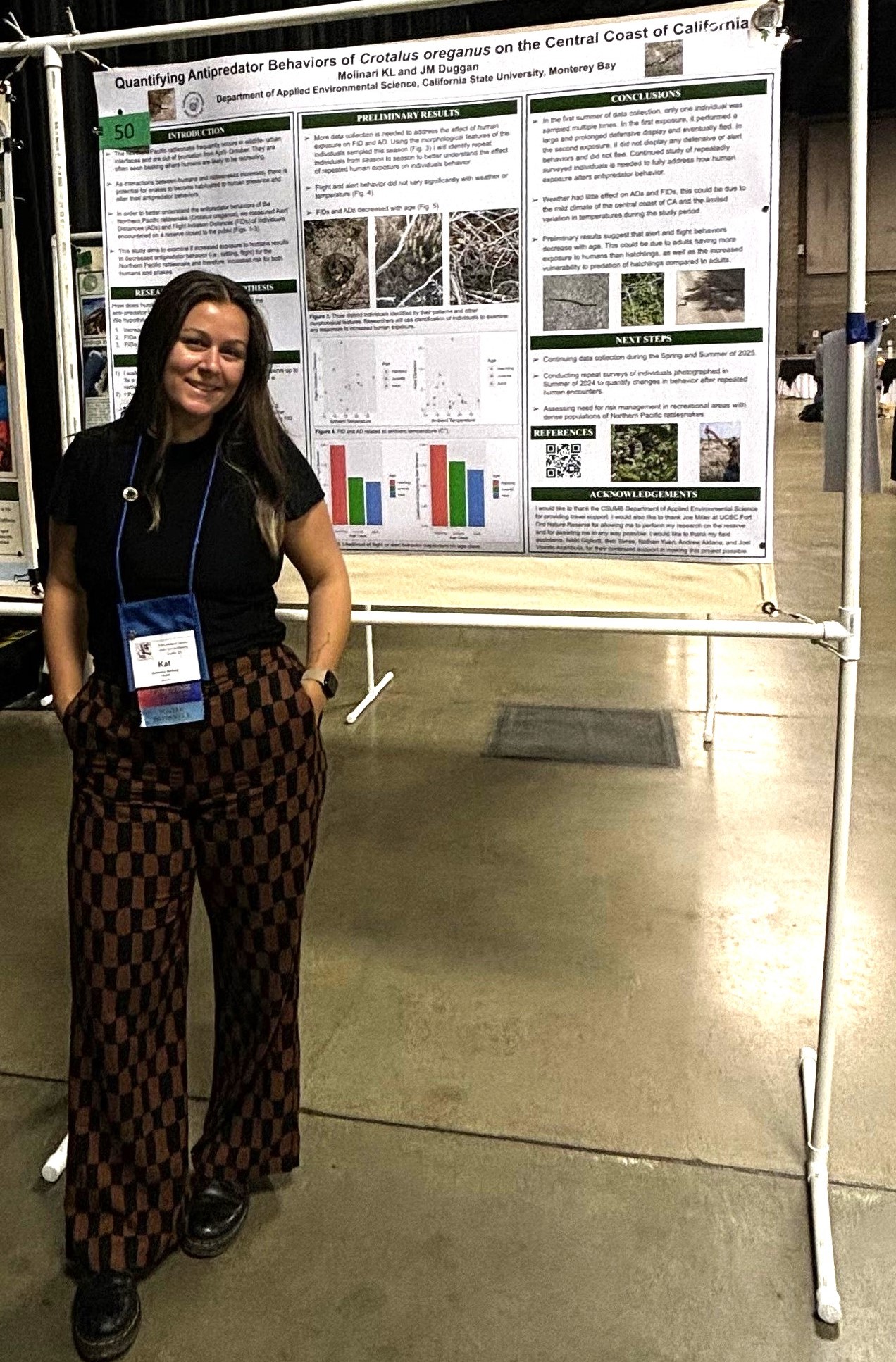 Kat standing in front of her scientific poster at a conference.