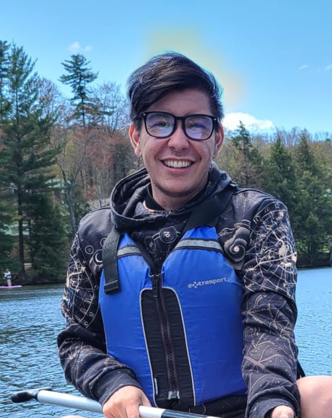 Kieran smiling for the camera, wearing a life vest while rafting.