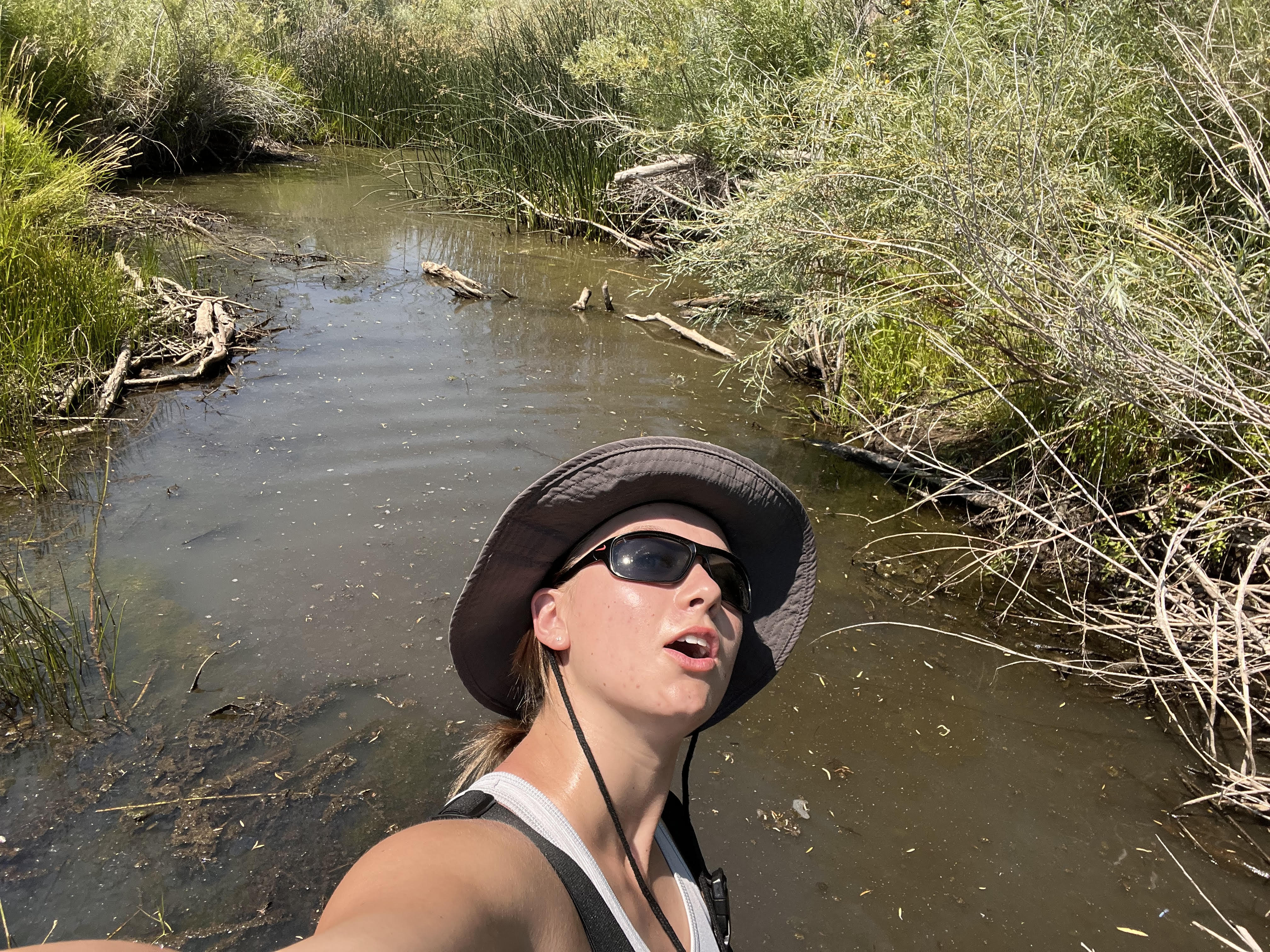 Rebecca taking a selfie while standing in a creek.