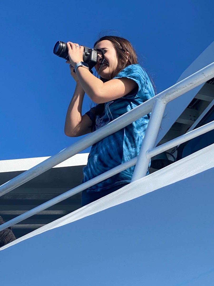 Ashley taking photos on a whale watching boat