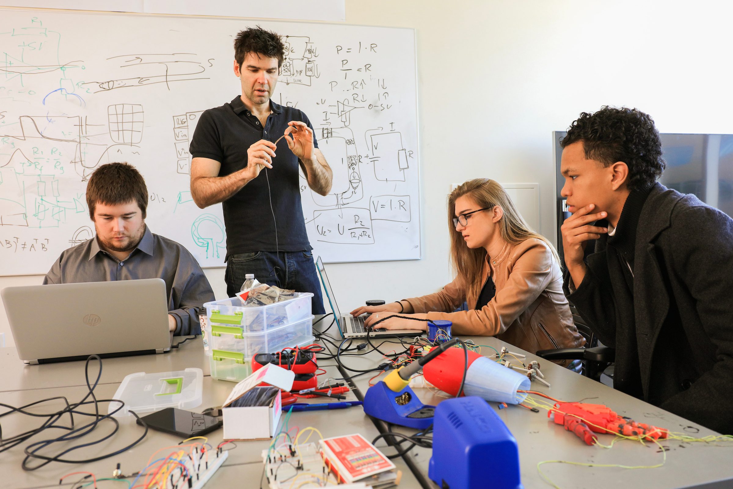 three students and one instructor fixing an artificially intelligent hand