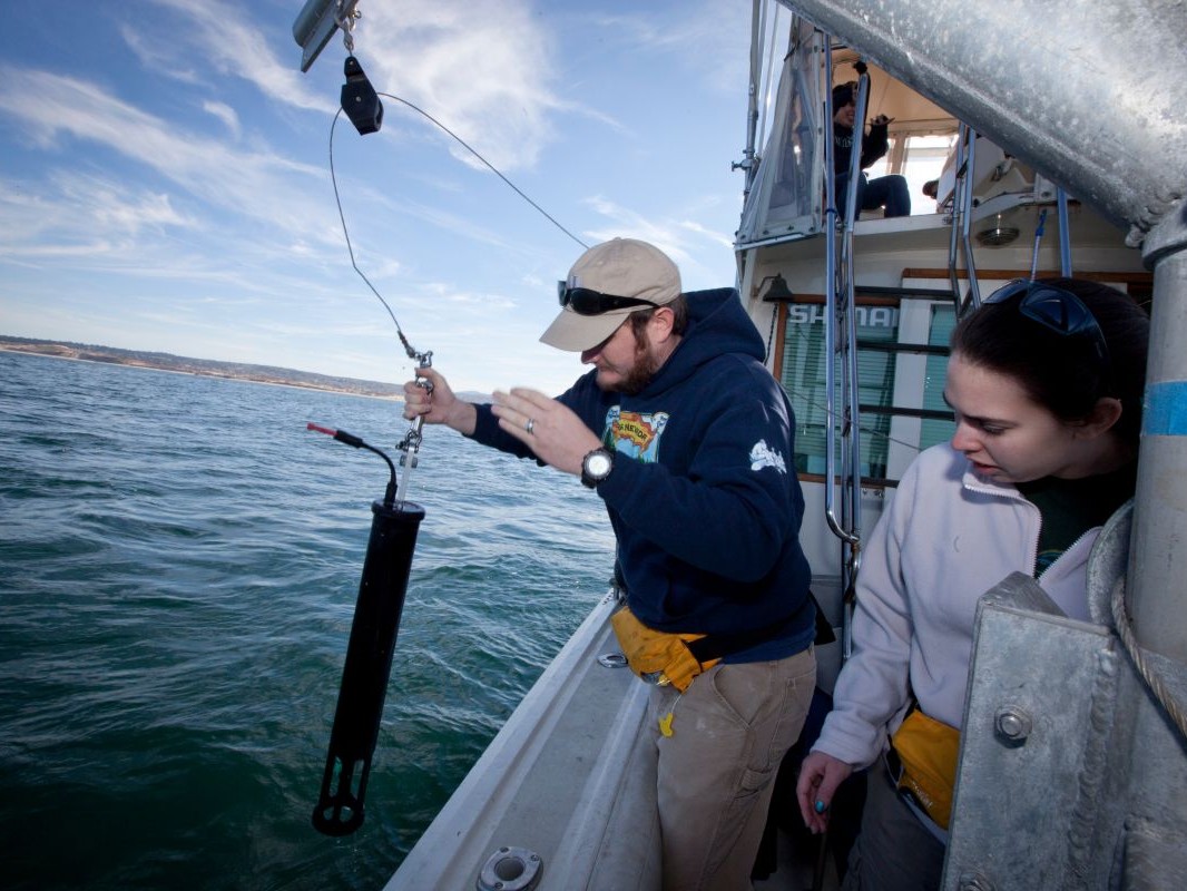 Science student deploys a measuring instrument over the side of a boat