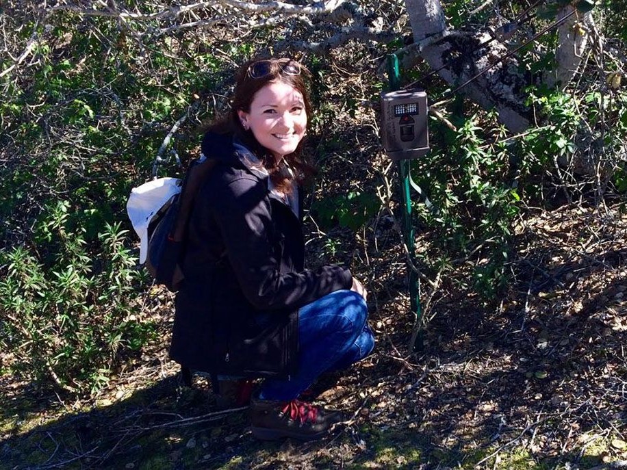 Science student kneeling near a shrub