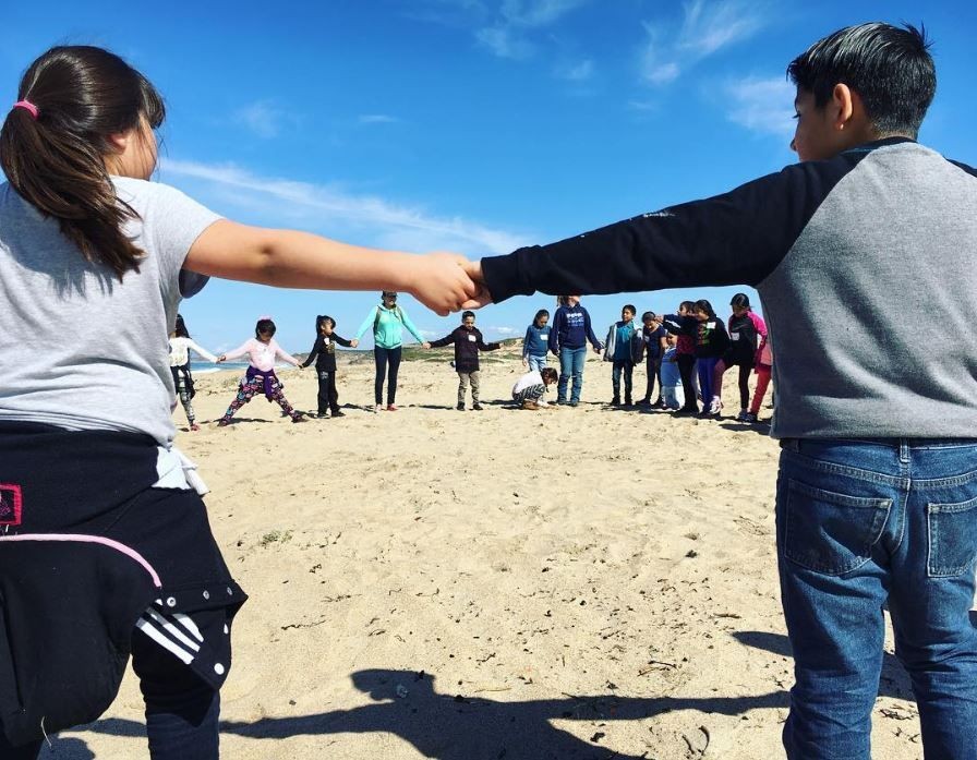 Group of school-aged travelers working with R.O.N. in Monterey State Beach