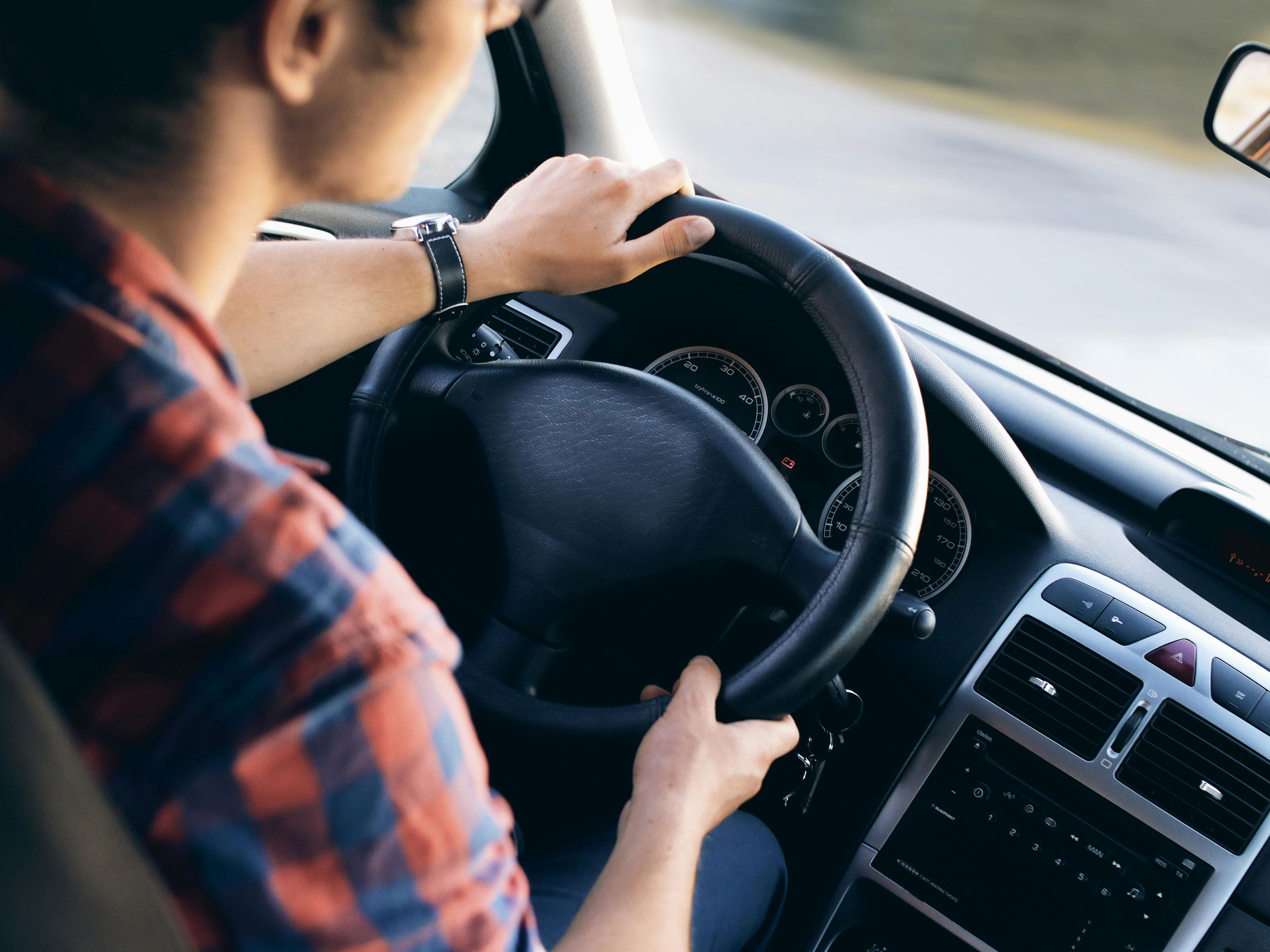 Someone driving a car with both hands on the steering wheel