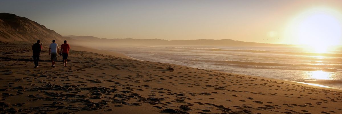 People walking on the beach during sunset.