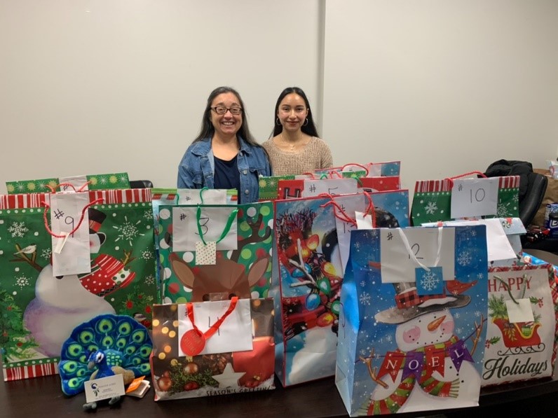 two students standing by christmas bags