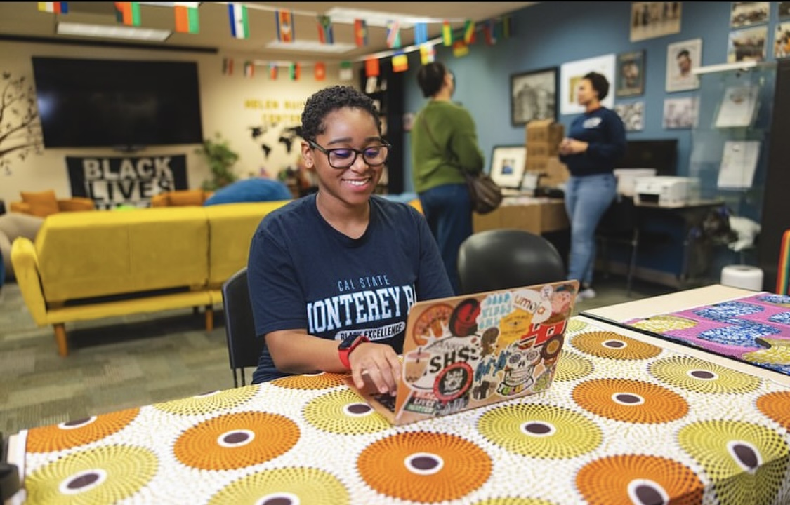 smiling student wearing glasses looking at laptop screen