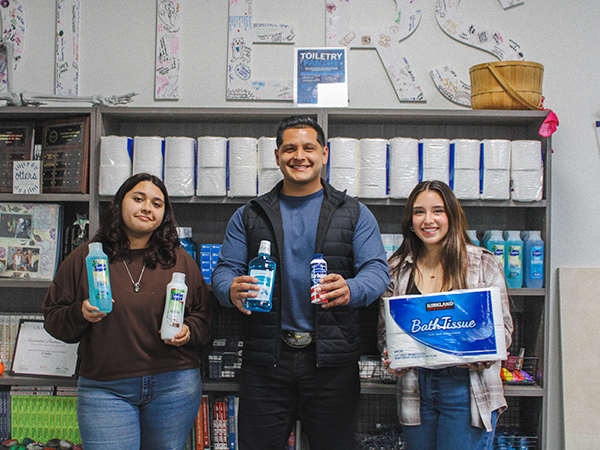 Three students visiting the Associated Students Toiletry Pantry holding 3 full sized items