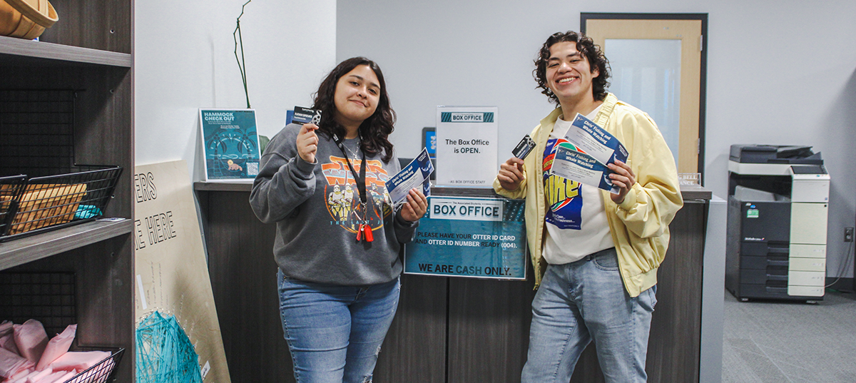 Two students holding box office tickets including movie tickets and whale watching tickets