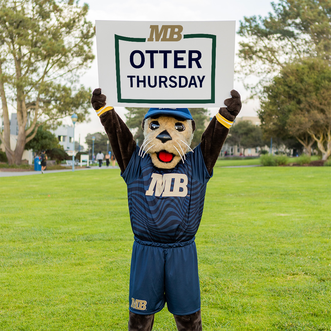 CSUMB Mascot Monte the Sea Otter outside holding a sign that reads 