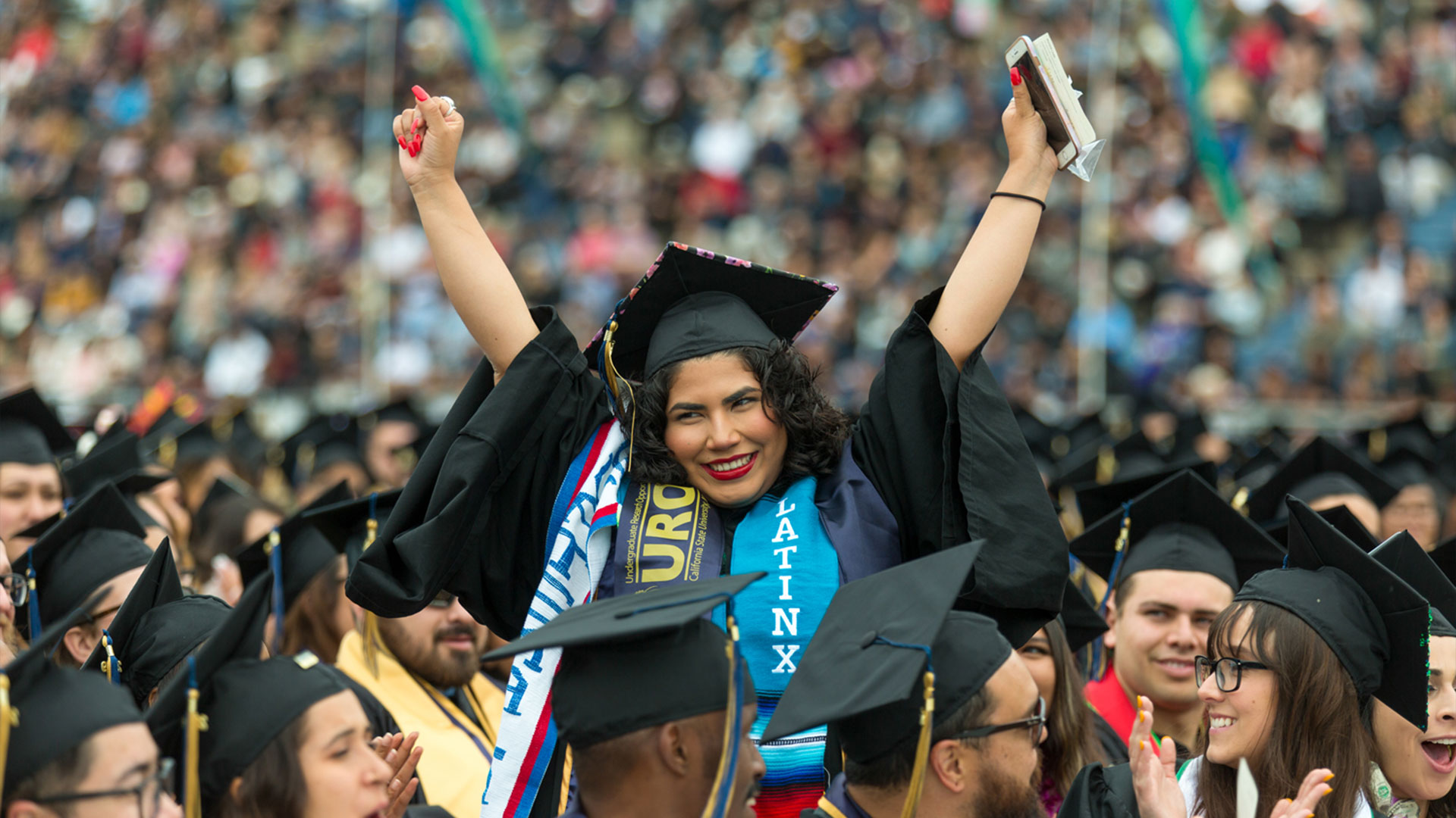 Photo: Graduate with Latinx stole, arms raised, cheering