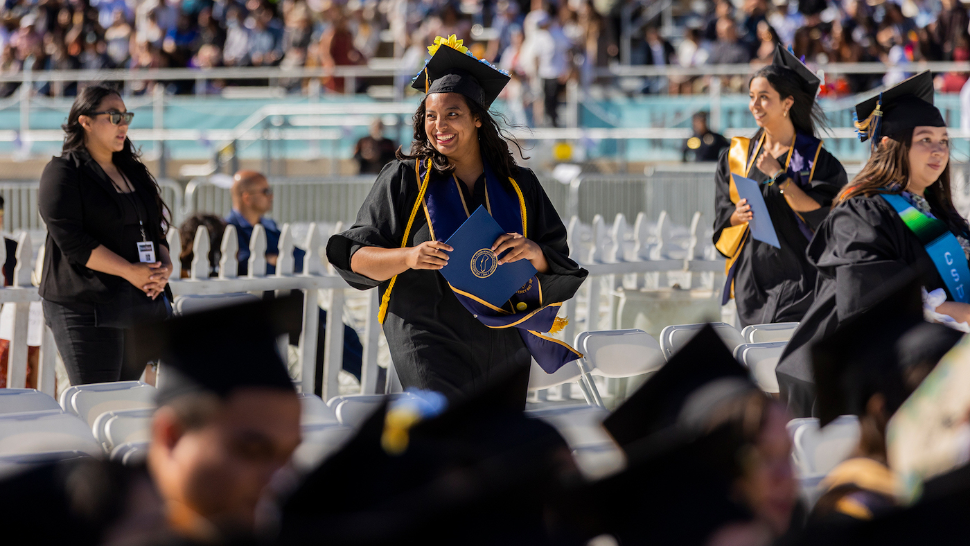 Photo: Graduate walking and holding diploma