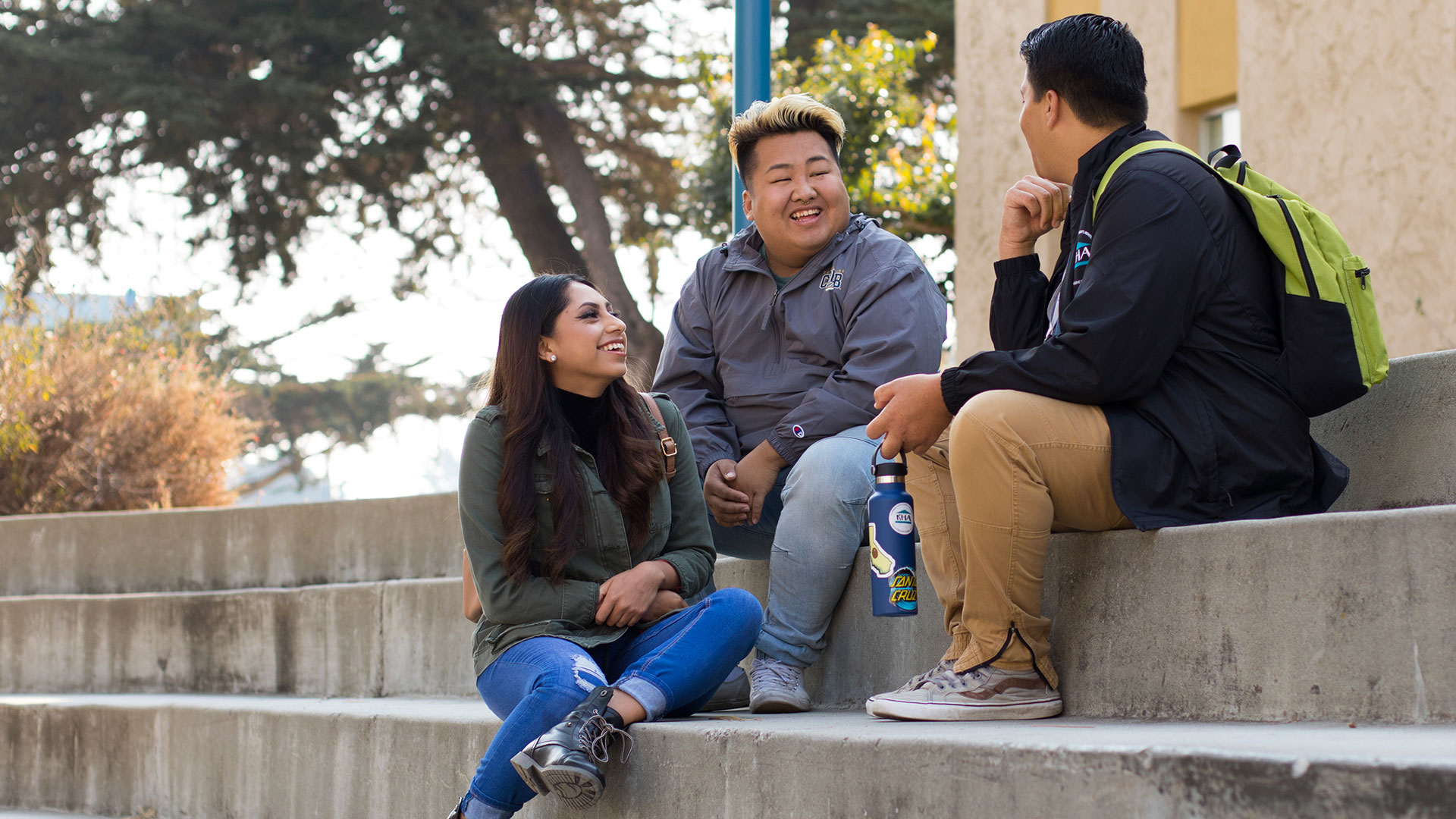 Three students talking on concrete steps.