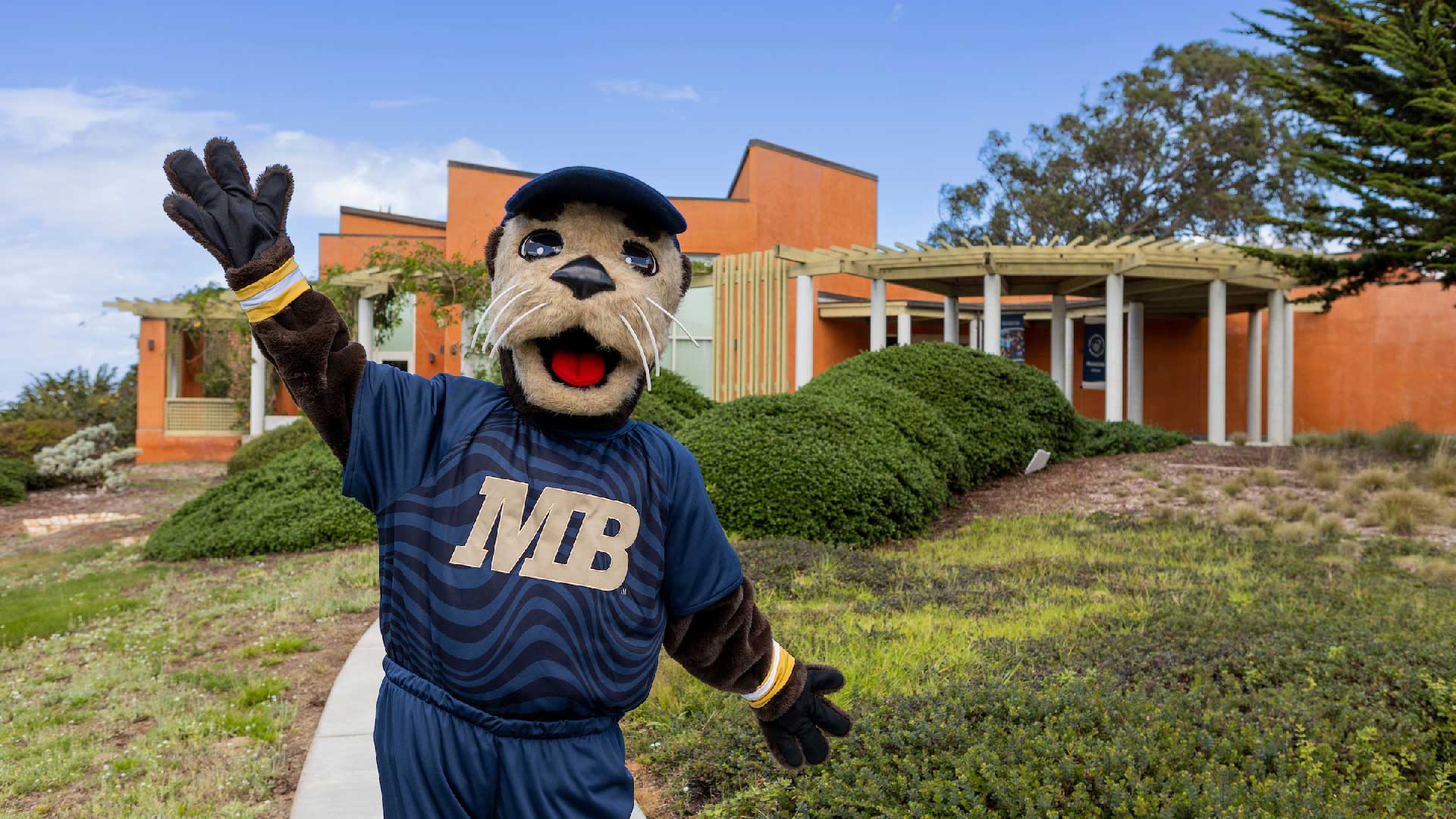 Monte Rey, CSUMB mascot, posing in front of the Alumni and Visitor Center Building