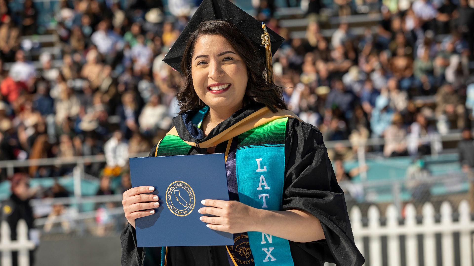 Latinx Grad holding diploma at the 2022 Commencement | Photo by Brent Dundore-Arias