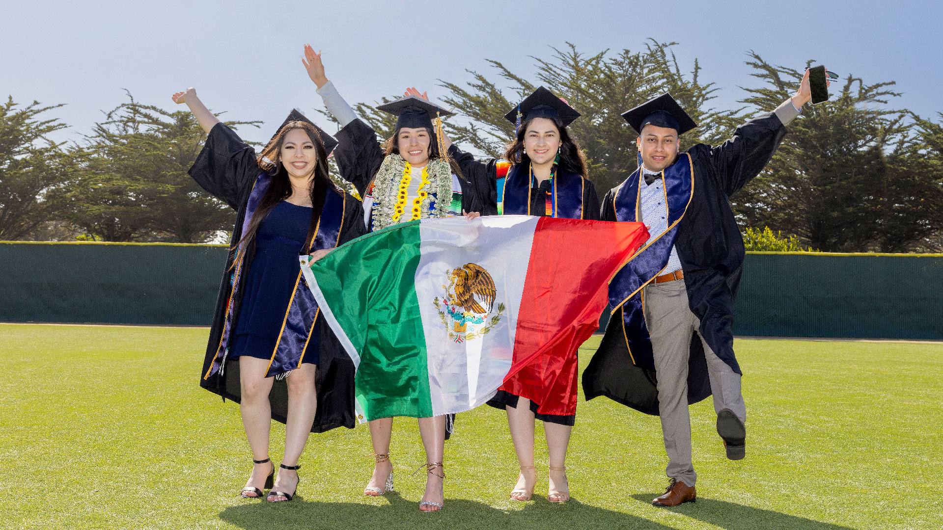 Latinx Grads holding the Mexico flag at the 2022 Commencement | Photo by Brent Dundore-Arias