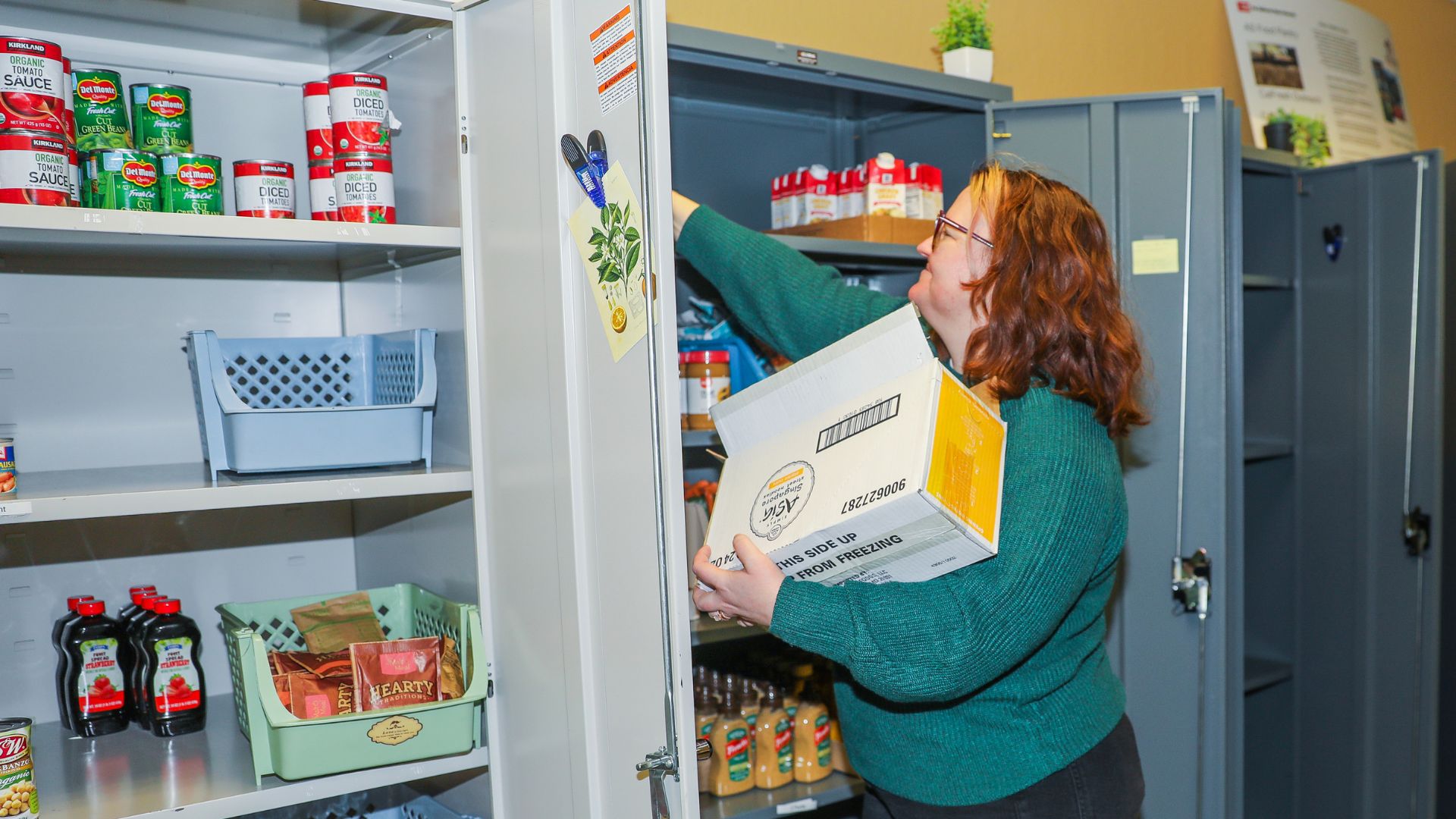 Basic Needs coordinator Robyn DoCanto stocks shelves in the pantry, which provides food-insecure students with important nutrition.