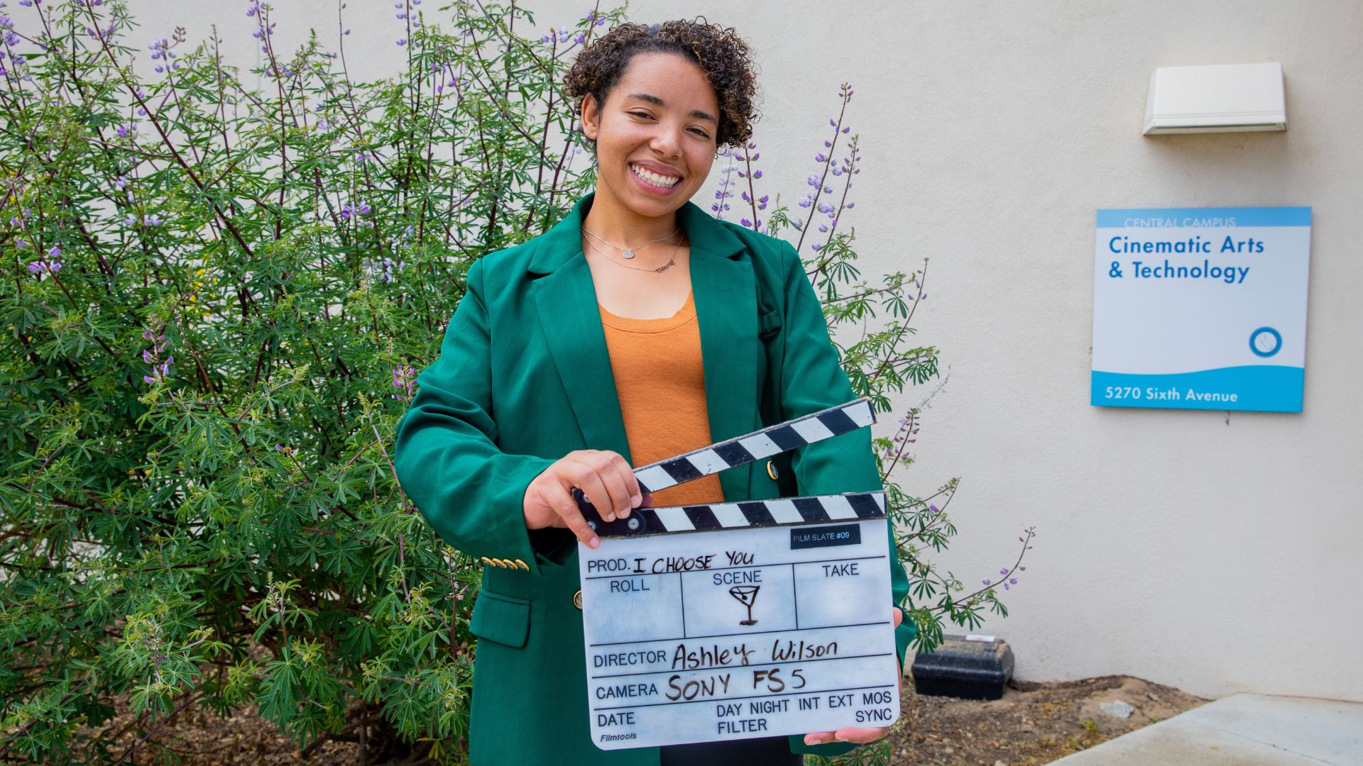 Ashley Wilson with film clapboard promoting her capstone film